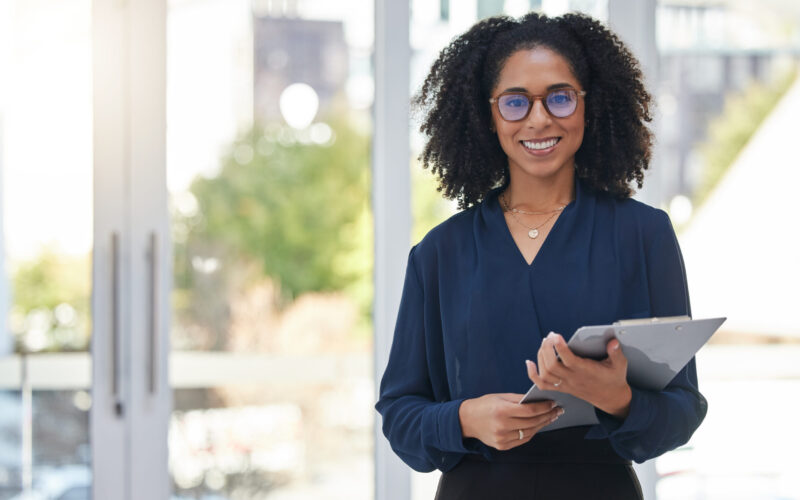 Portrait, checklist and business woman in office happy, smile and confident with positive mindset. Leader, face and female corporate employee with clipboard for management, schedule and agenda.